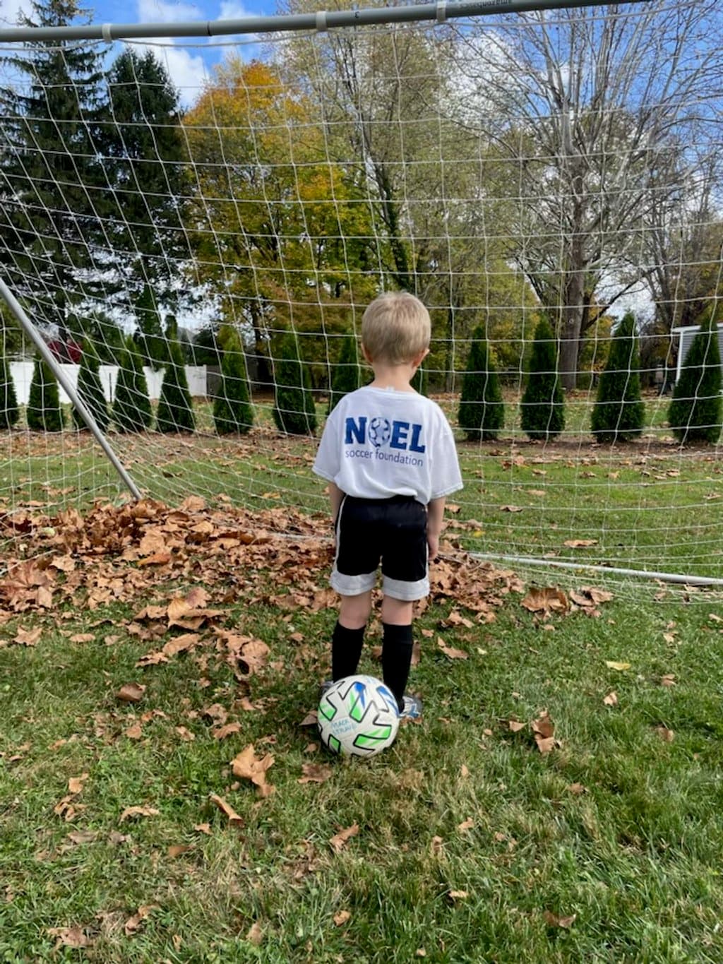 Young Lighthouse Soccer Club player in a new jersey with a soccer ball in front of the goal